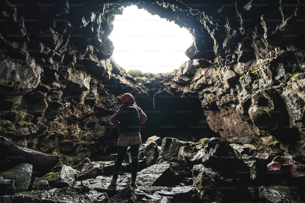 Une voyageuse explore un tunnel de lave en Islande. Raufarholshellir est un beau monde caché de grotte. C’est l’un des tunnels de lave les plus longs et les plus connus d’Islande, en Europe, pour des aventures incroyables.