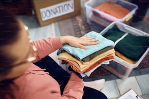 Nahaufnahme einer weiblichen Freiwilligen, die gespendete Kleidung in Kisten organisiert.