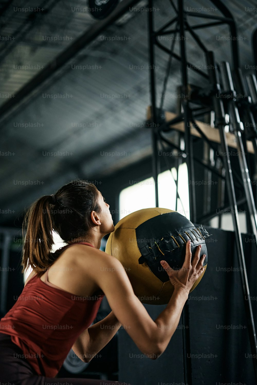 Athletic woman exercising squats while holding medicine ball during cross training in a gym. Copy space.