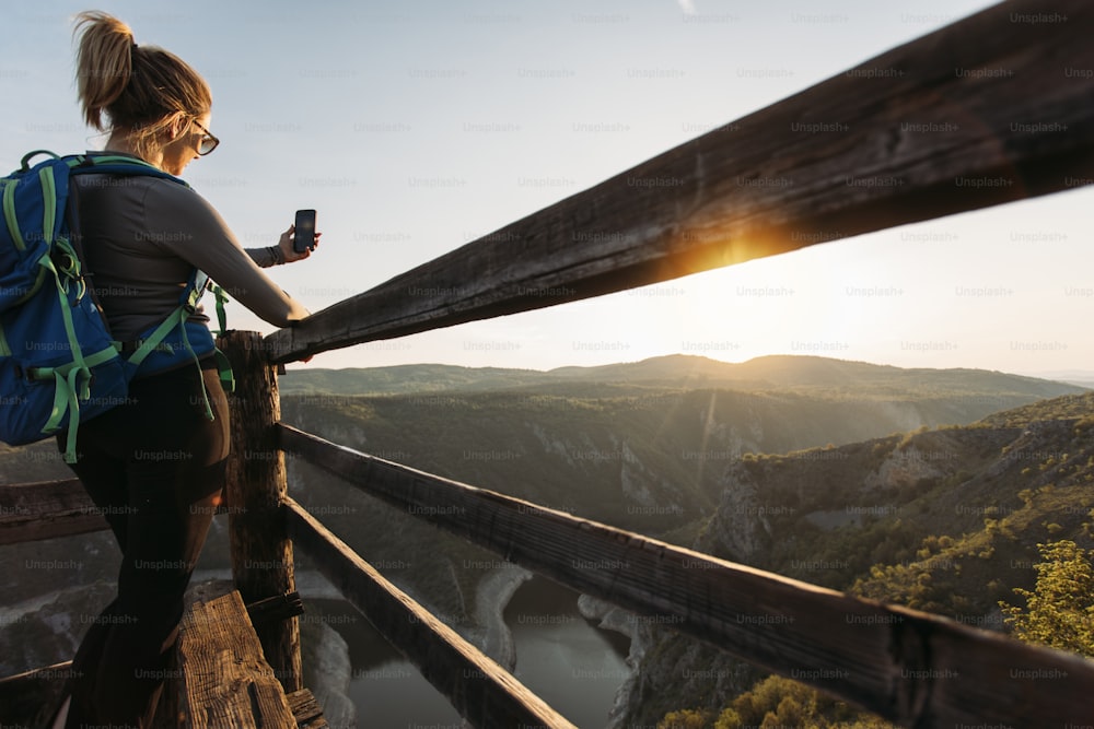 협곡 관점에서 스마트폰으로 사진을 찍는 젊은 여성 등산객.