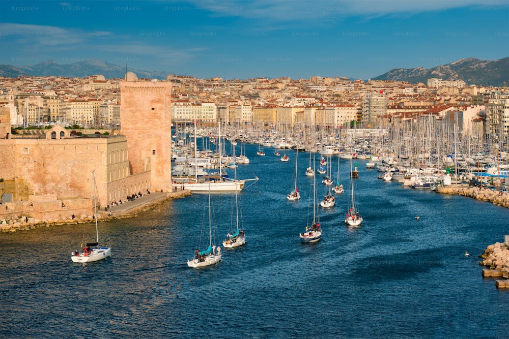 Yachts coming from boat regatta to Marseille Old Port (Vieux-Port de Marseille) on sunset and Fort Saint-Jean. Marseille, France