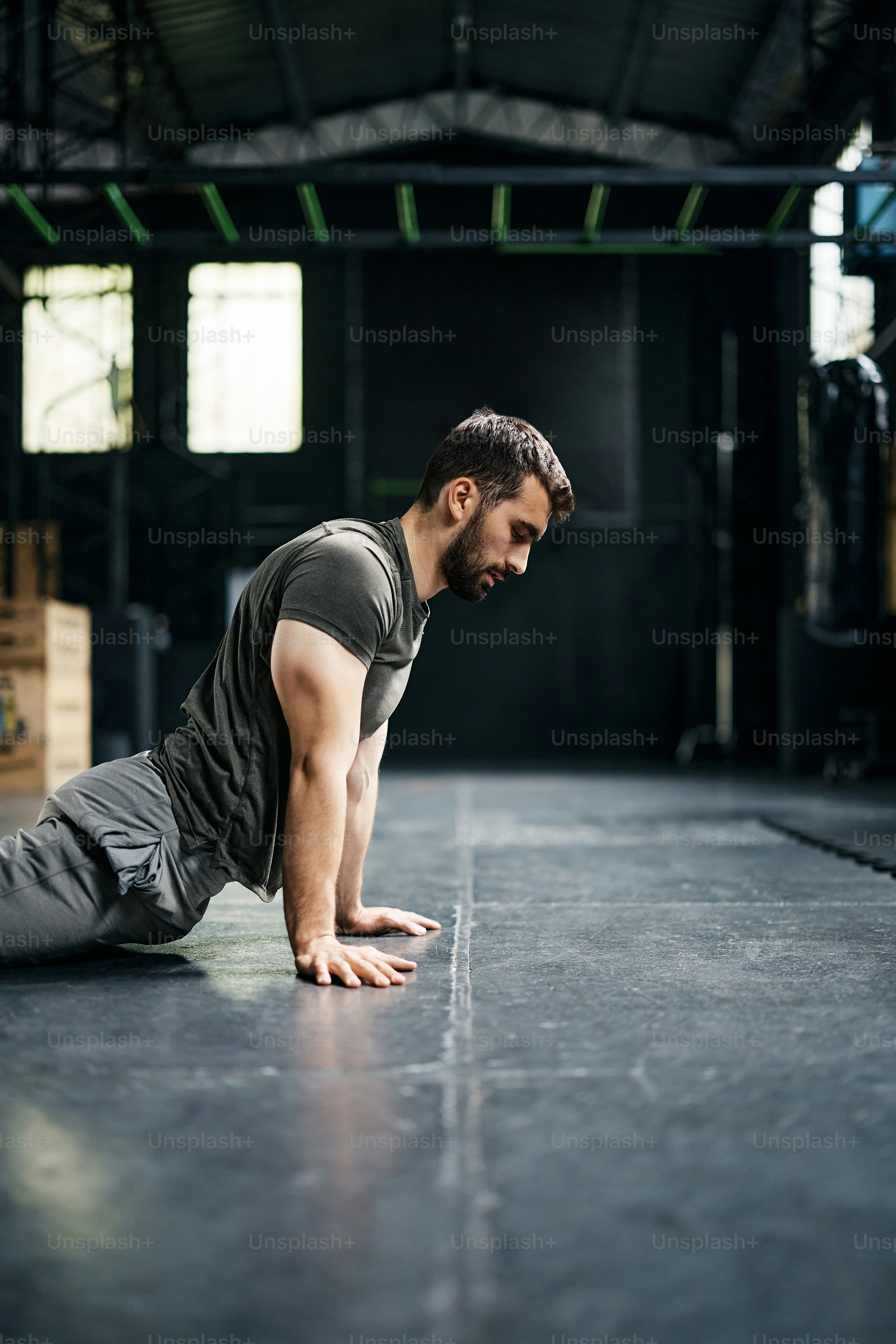 Hombre atlético calentando para el entrenamiento deportivo mientras hace ejercicio en un gimnasio. Espacio de copia