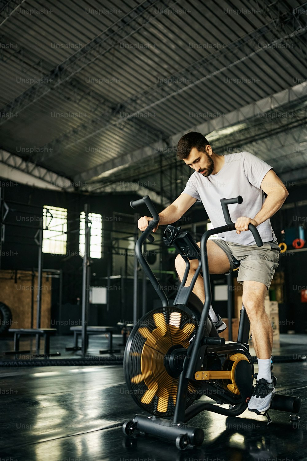 Male athlete exercising on exercise bike during cross training in a gym.