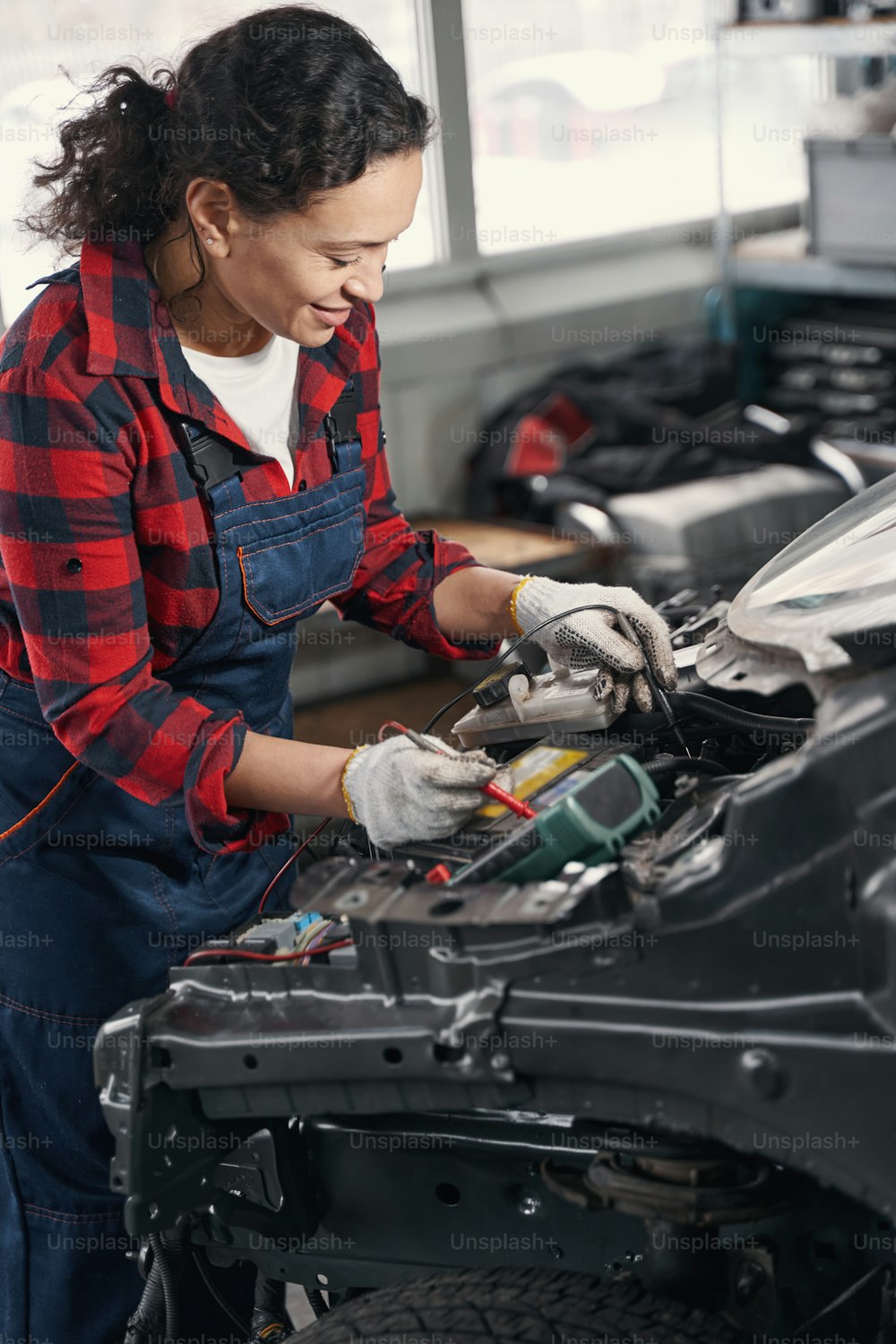 Glücklicher Mechaniker lächelt, während er Spezialwerkzeuge benutzt, Auto repariert