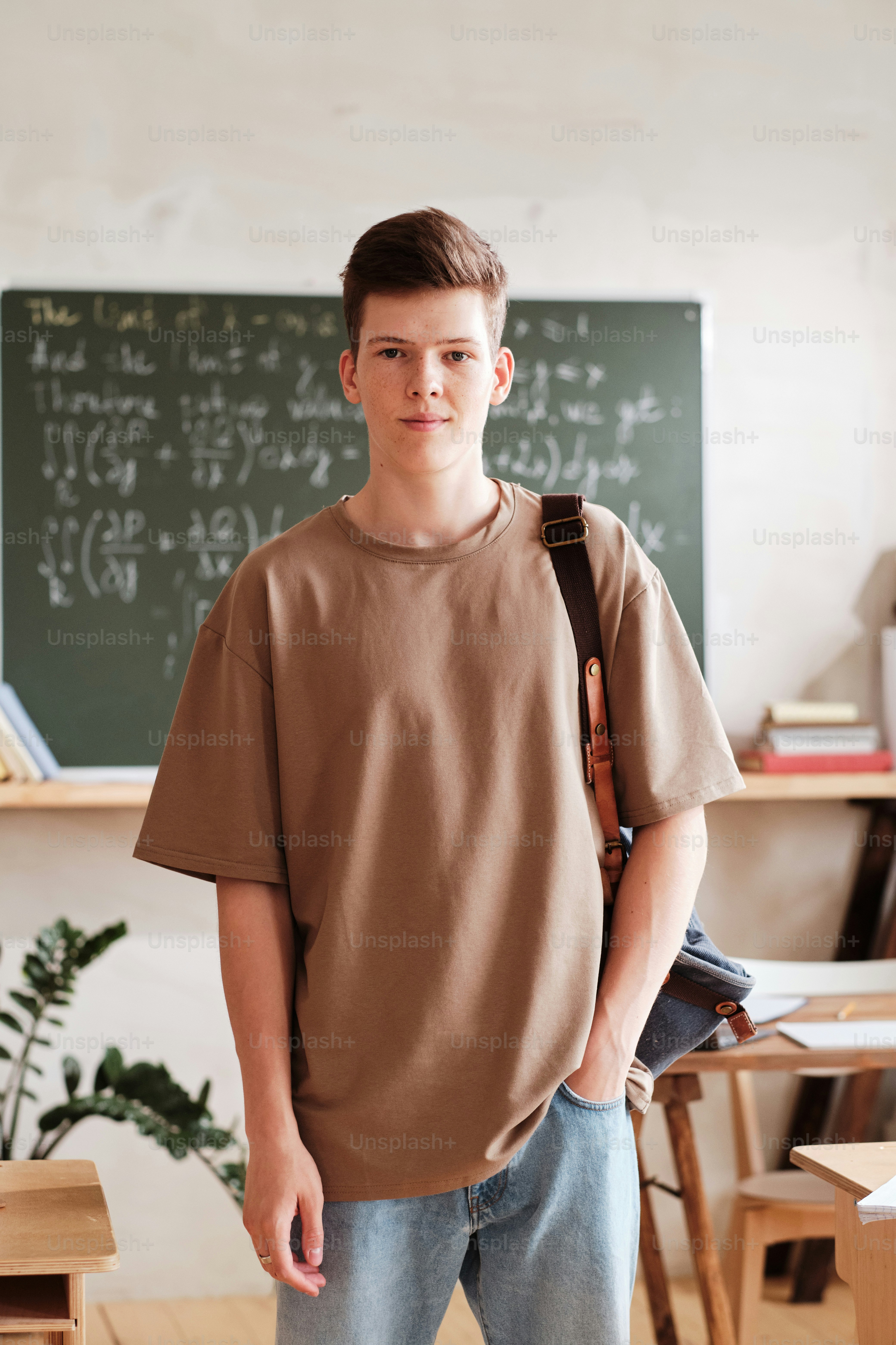 Portrait of schoolboy with backpack looking at camera while standing in the classroom