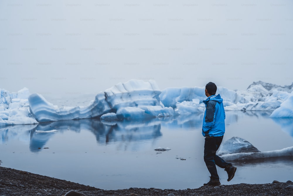 Homem viajante viaja para Jokulsarlon bela lagoa glacial na Islândia. Jokulsarlon é um destino famoso no Parque Nacional Vatnajokull, sudeste da Islândia, Europa. Natureza gelada do inverno.