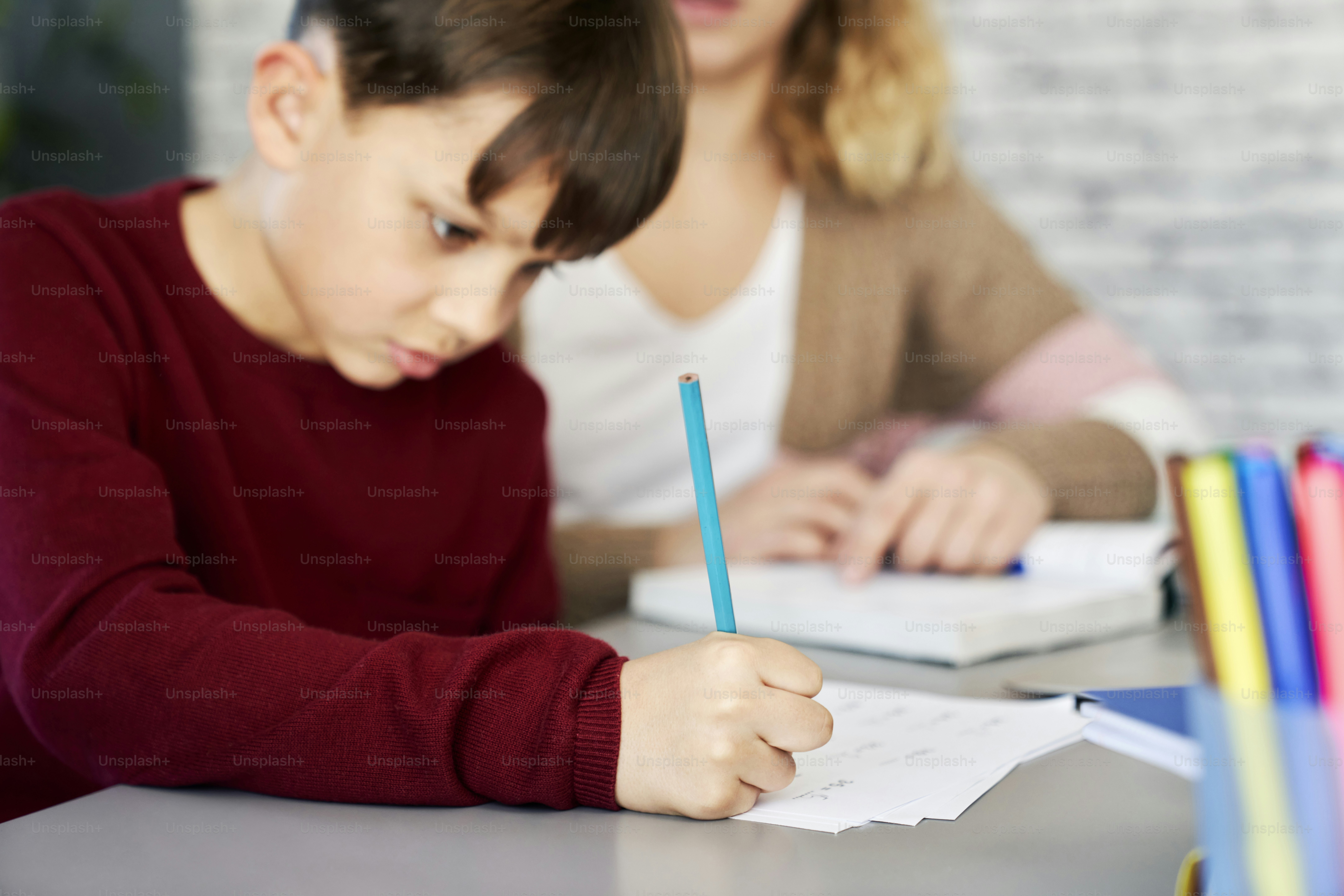 Close up of schoolboy doing homework at home with mom