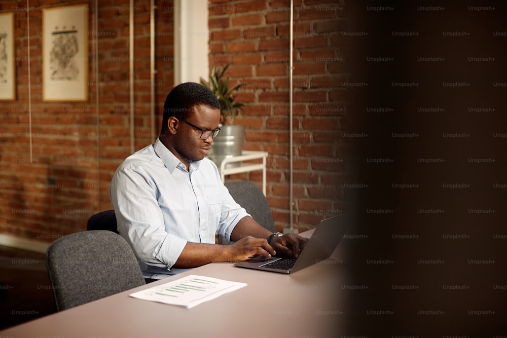 Empreendedor afro-americano usando o computador enquanto trabalha no escritório. Espaço de cópia.