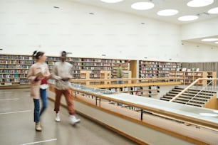 Movimento sfocato di persone che camminano lungo il corridoio in una grande biblioteca