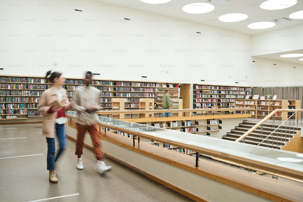 Movimento borrado de pessoas andando ao longo do corredor em grande biblioteca