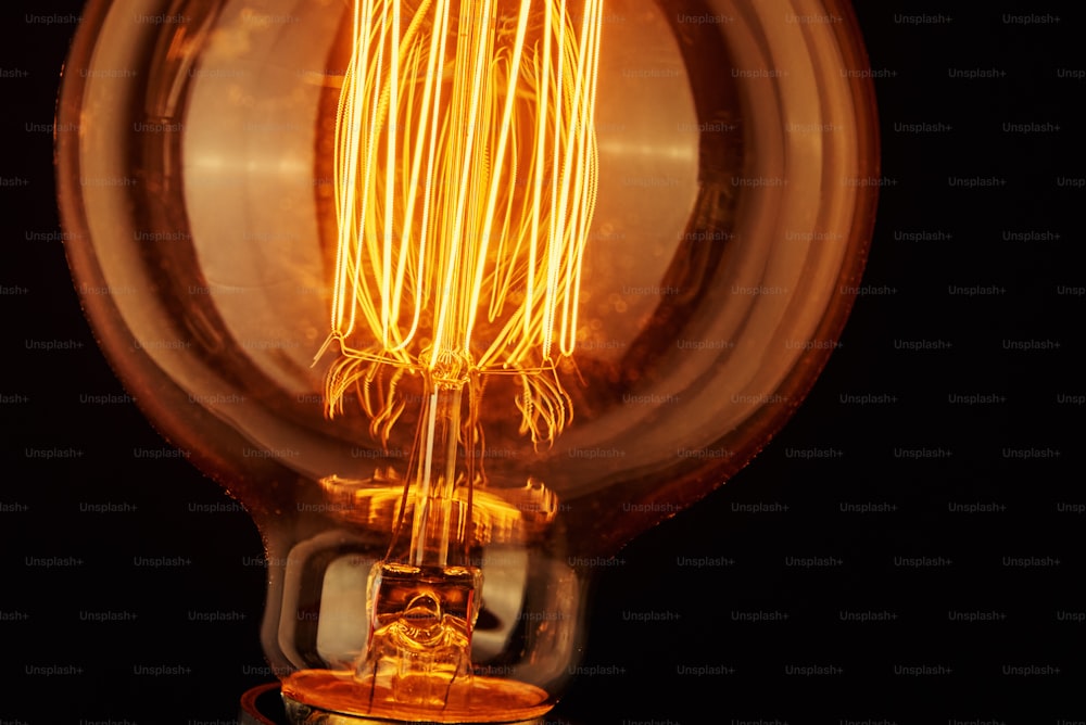 Vintage-Glühbirne auf schwarzem Hintergrund, Nahaufnahme Glühende Edison-Glühbirne