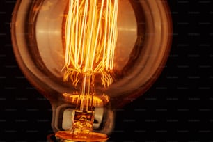 Vintage light bulb on black background, close up Glowing edison bulb