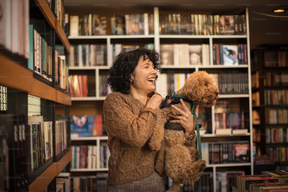 Mulher feliz com seu cão na biblioteca.