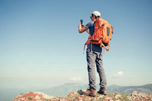 Hiker fotógrafo tirando foto usando um telefone inteligente.