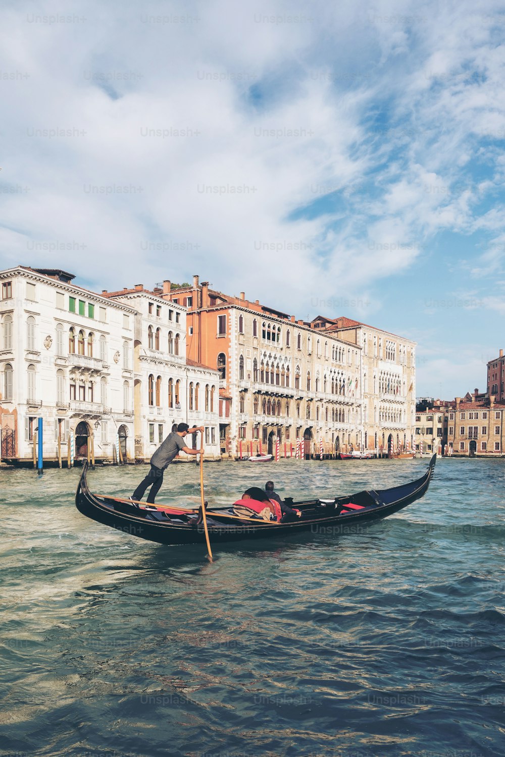 Venetian gondolier punting gondola through grand canal of Venice, Italy. Gondola is a traditional, flat-bottomed Venetian rowing boat. It is the unique transportation of Venice, Italy.