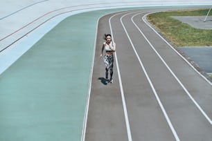 Vista superior de cuerpo entero de una mujer joven con ropa deportiva corriendo mientras hace ejercicio al aire libre