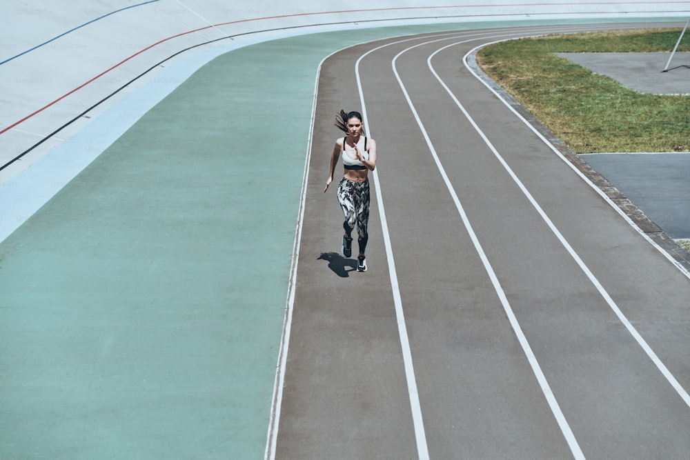 야외에서 운동하는 동안 달리는 스포츠 의류를 입은 젊은 여성의 전체 길이 평면도