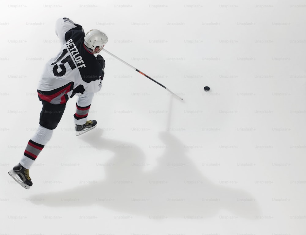 Un hombre con uniforme blanco y negro está jugando hockey sobre hielo