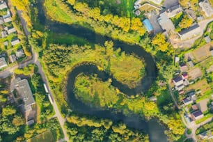 Top aerial view of the natural rural landscape valley of a meandering river among green fields and forests