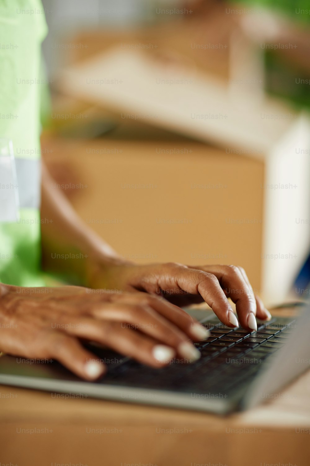 창고의 보관함에서 노트북으로 작업하는 아프리카계 미국인 여성의 클로즈업.