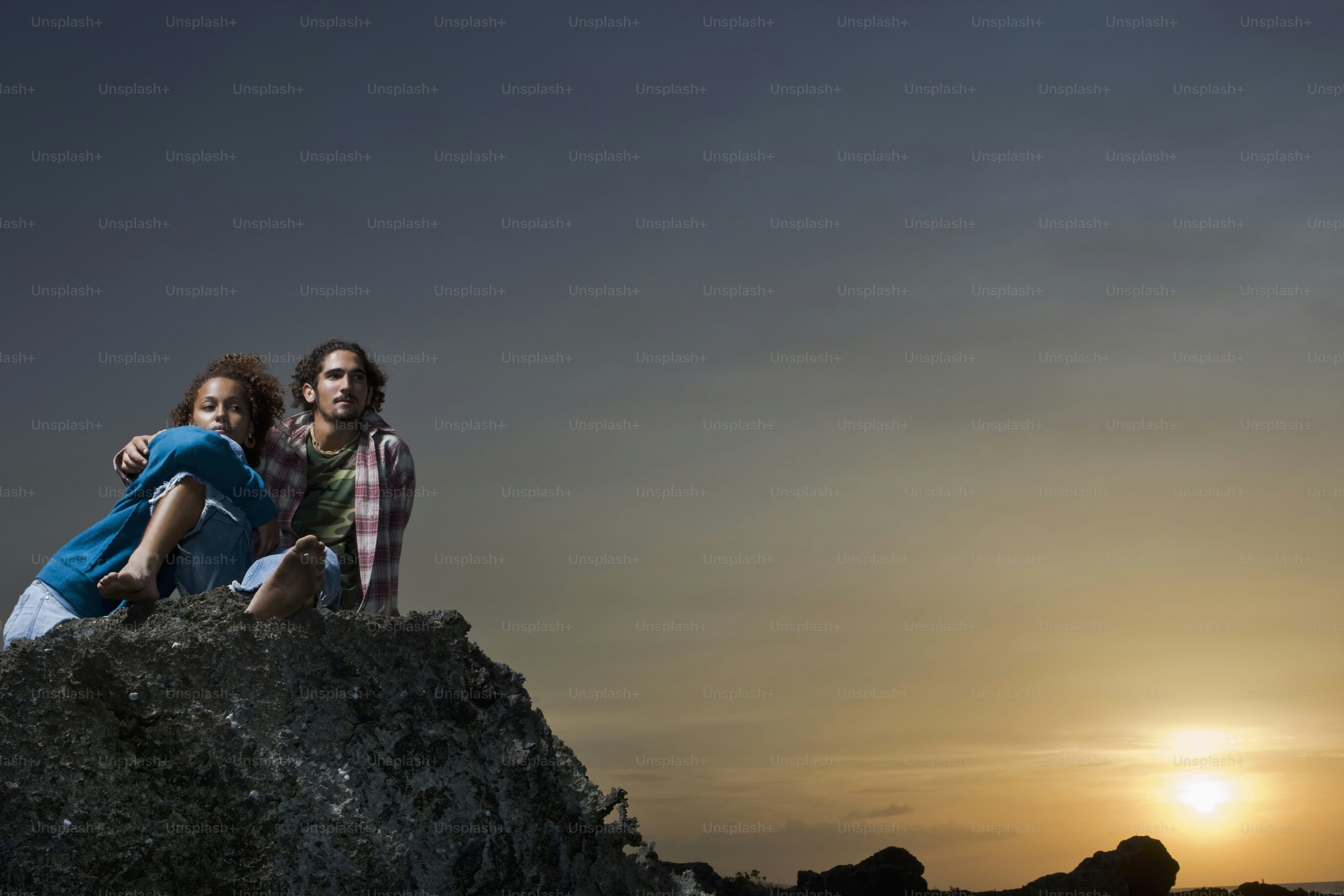 A couple of people sitting on top of a rock photo – Copy space Image on ...