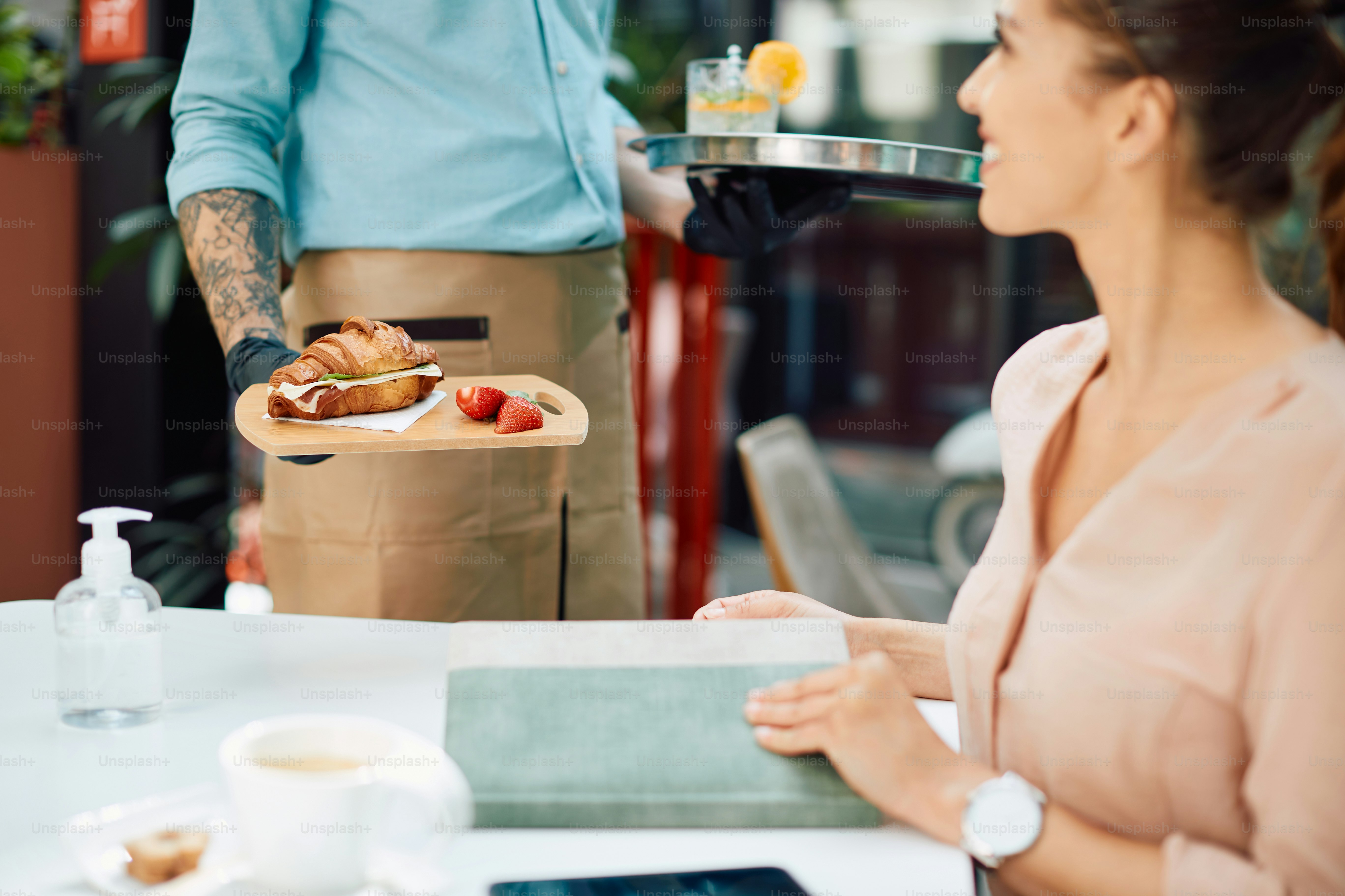 Foto Primer plano de un camarero que sirve un sándwich de croissant a ...