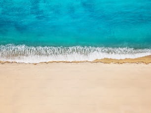 Aerial view of an idyllic sea sandy beach with an incoming azure wave. The concept of holidays in tropical countries and relaxation. Background for travel and vacation