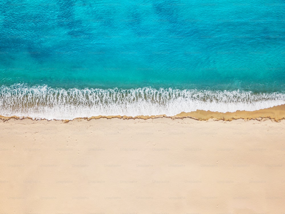 Aerial view of an idyllic sea sandy beach with an incoming azure wave. The concept of holidays in tropical countries and relaxation. Background for travel and vacation