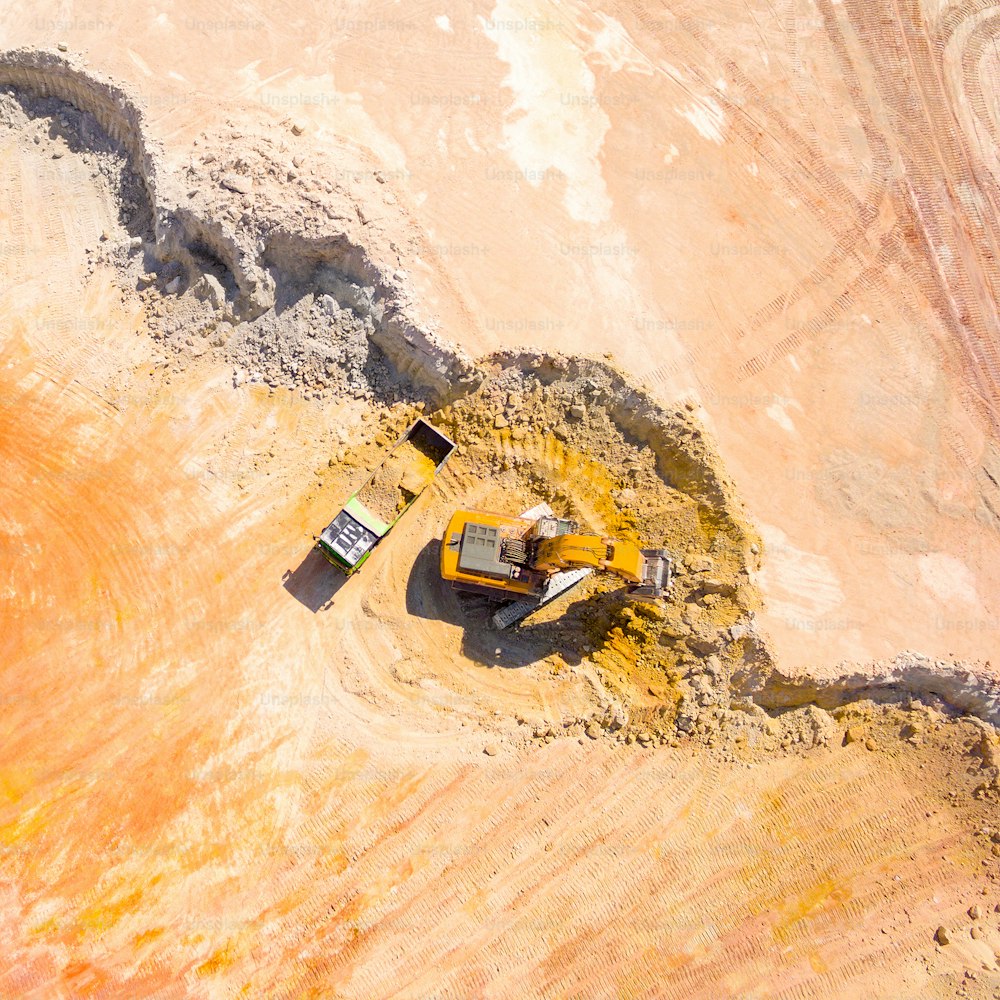 Veduta aerea di un escavatore che carica un camion nella miniera. Estrazione mineraria dall'alto. Sfondo industriale con fotografia da drone.
