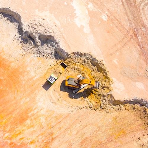 Vue aérienne d'un site d'exploitation de carrière avec excavateur chargeant un camion