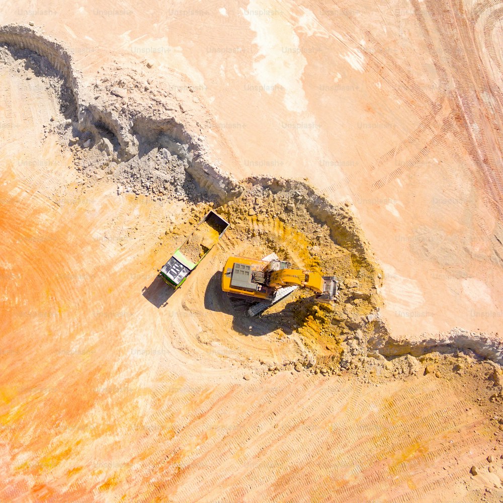 Aerial view of a excavator loading a truck in the mine. Mining from above. Industrial background with drone photography.
