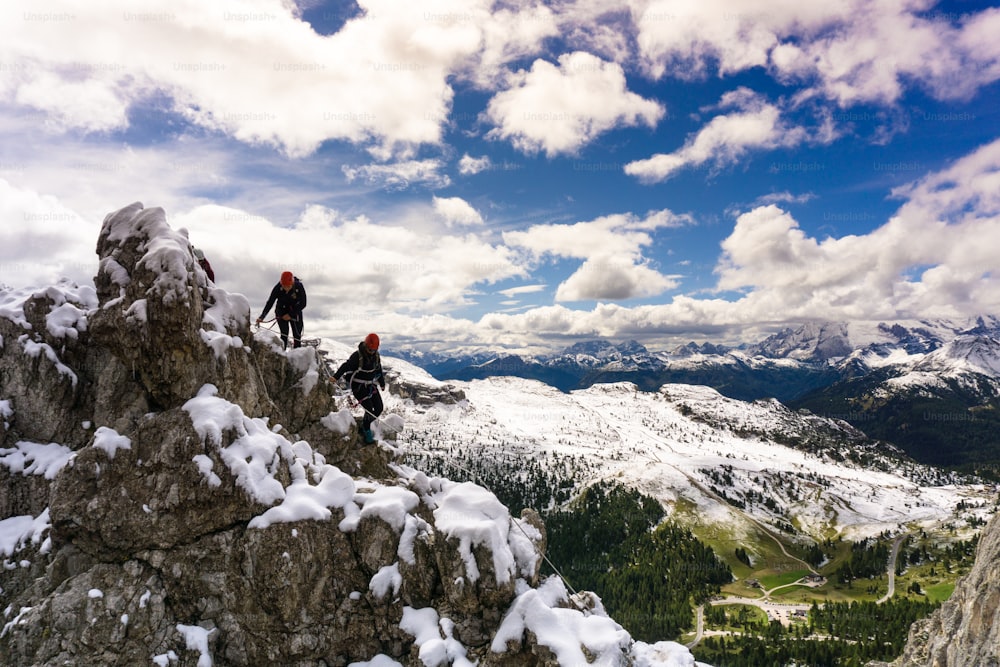 two young female climbers on a snowy and narrow ridge on an exposed Via Ferrata in the South Tyrol in the Italian Dolomites