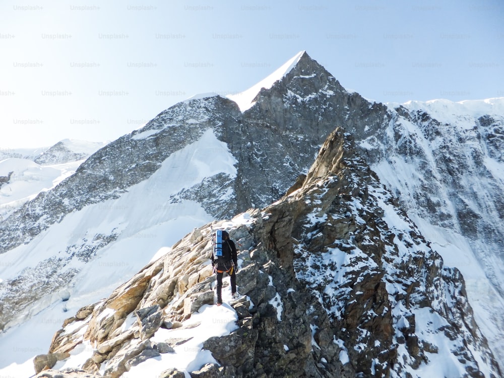 Bergführer begibt sich auf den Gipfel eines hochalpinen Gipfels, während er einen exponierten Felsrücken in der Nähe von INterlaken in der Schweiz erklimmt