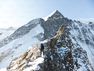 mountain guide heads towards the summit of a high alpine peak as he climbs an exposed rocky ridge near INterlaken in Switzerland