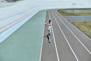 Vista trasera superior de una mujer joven con ropa deportiva corriendo mientras hace ejercicio al aire libre