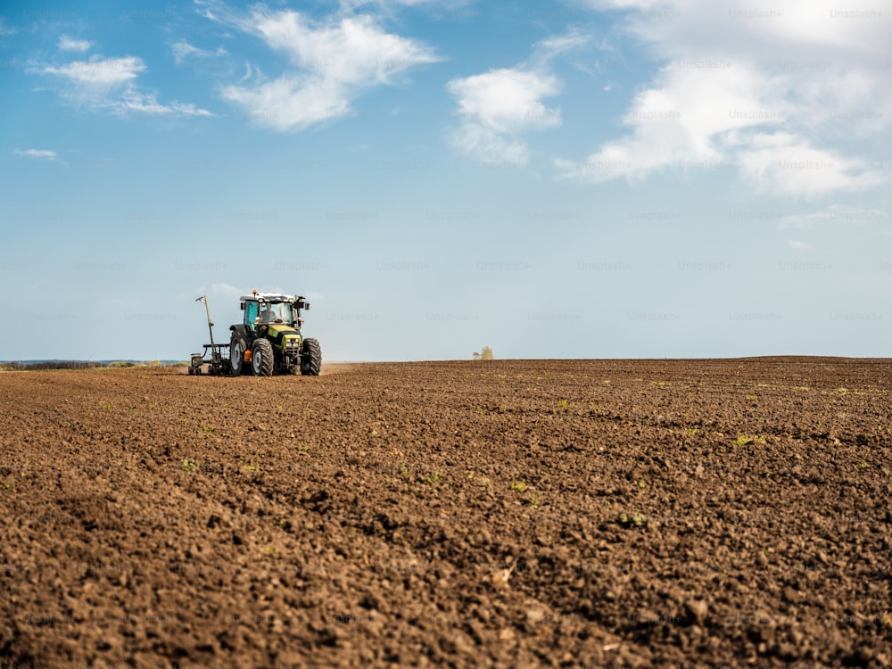 Farmer seeding, sowing crops at field. Sowing is the process of planting seeds in the ground as part of the early spring time agricultural activities.