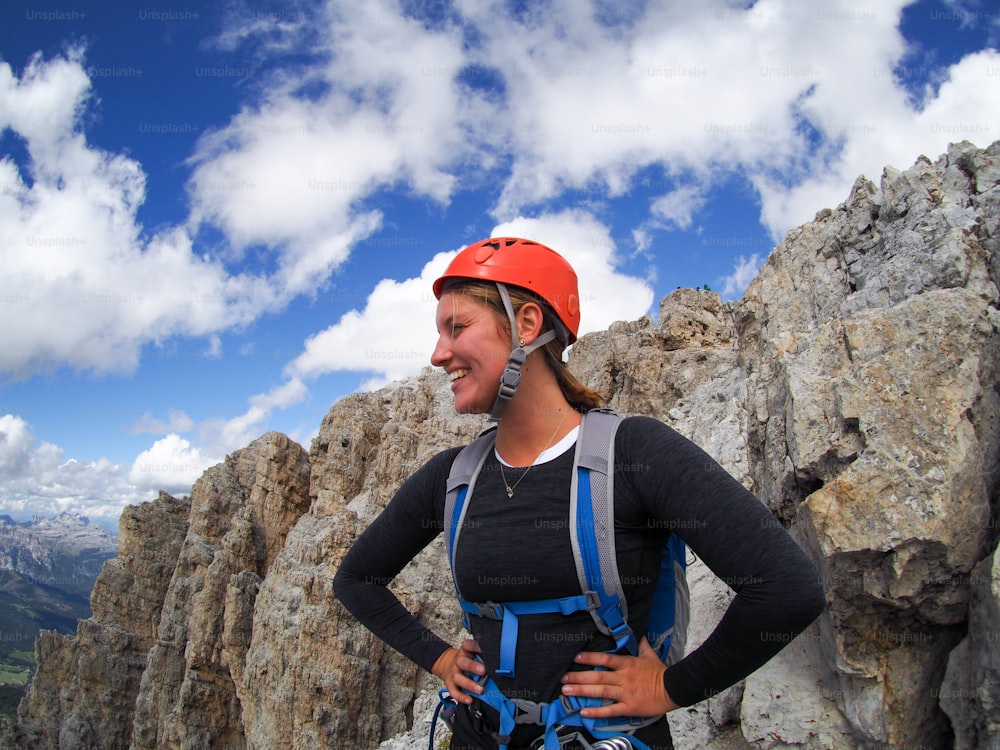 Uma alpinista feminina morena atraente em um pico de montanha nas Dolomitas olhando para a distância