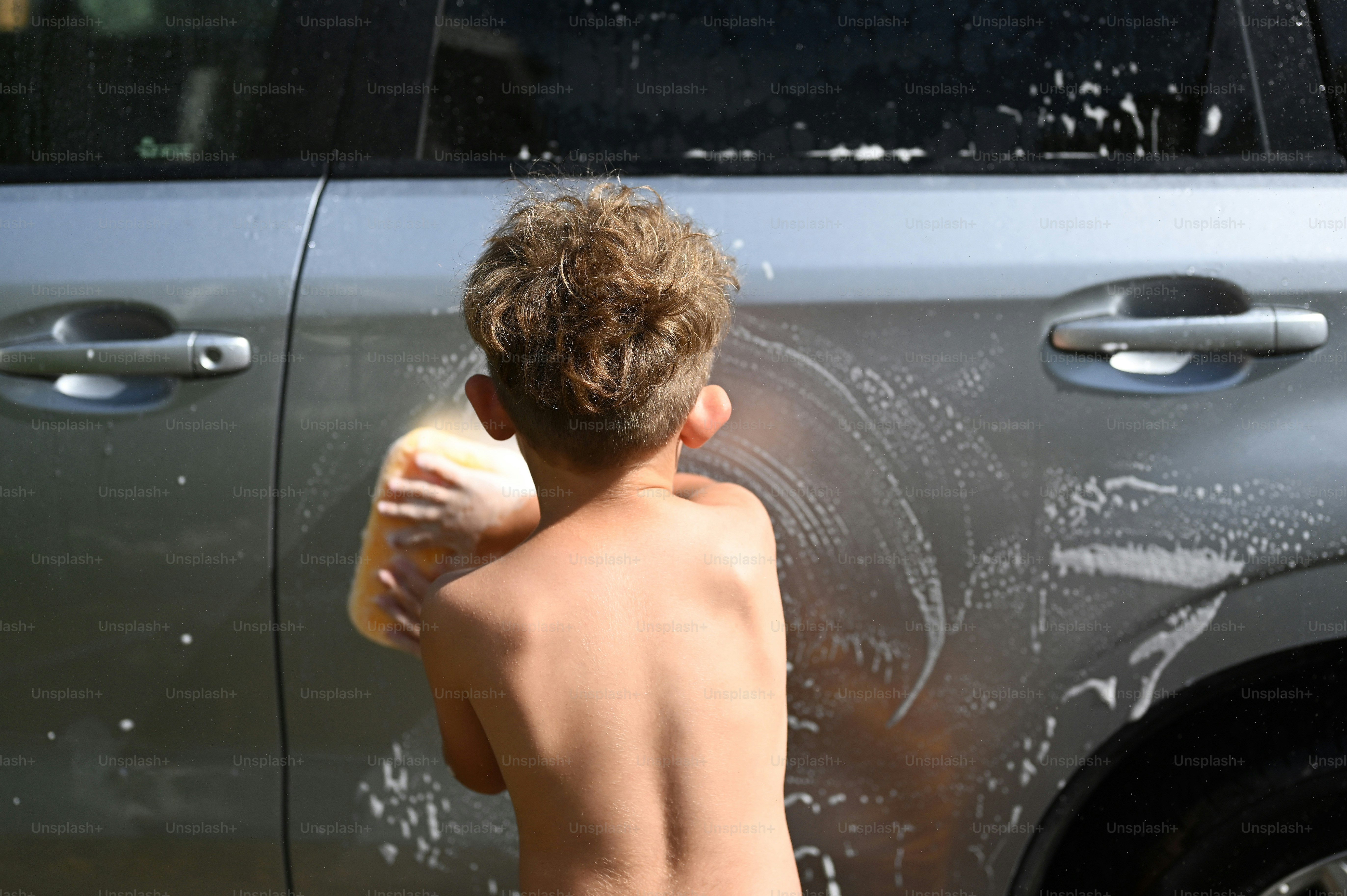 A young boy washing his car with a sponge photo – Car wash Image on ...