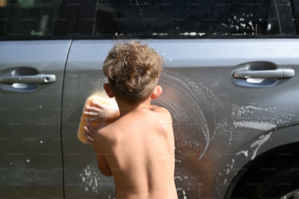 a young boy washing his car with a sponge