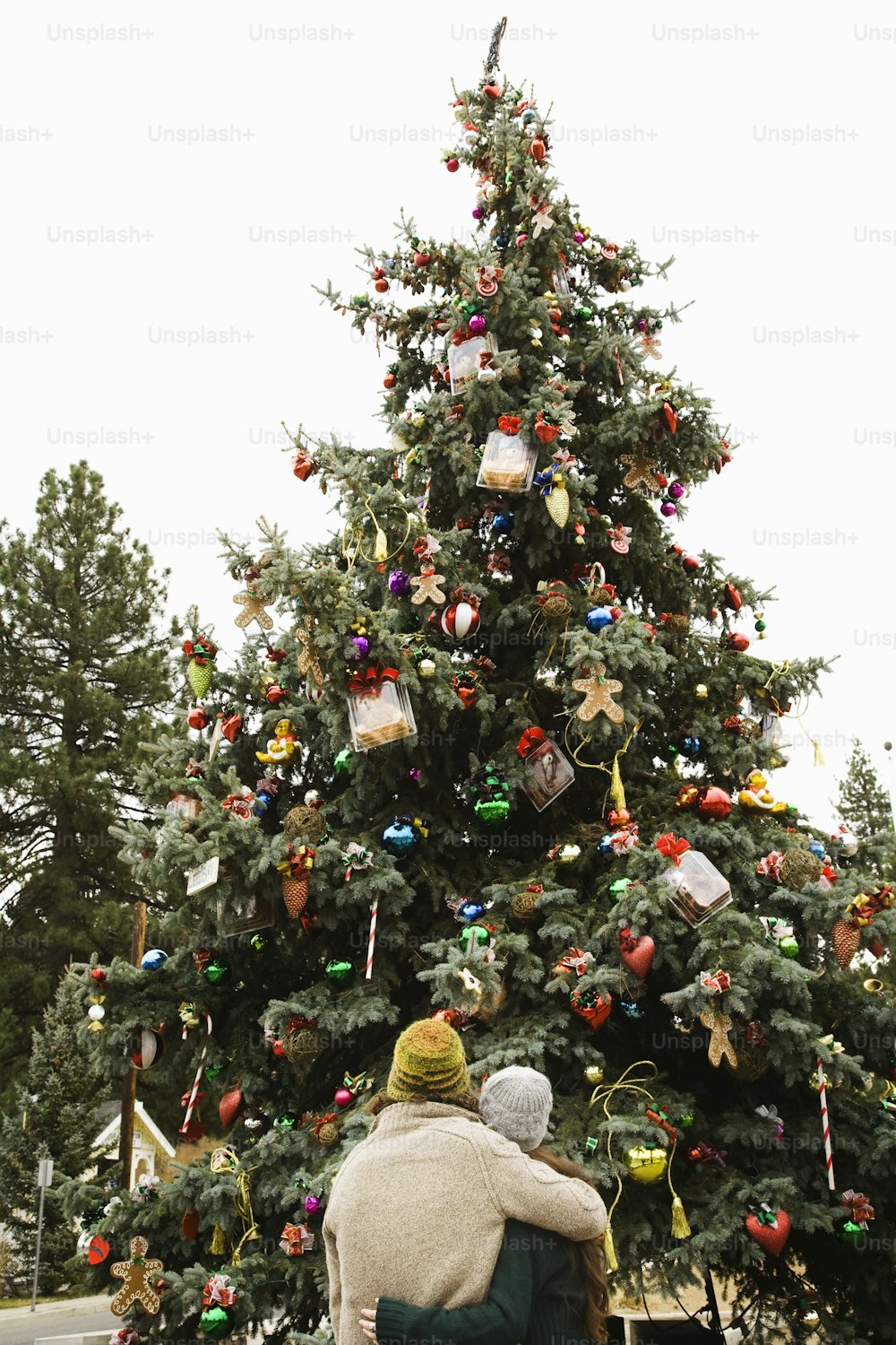 two people standing in front of a christmas tree