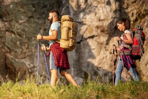 Excursionistas con mochilas y bastones de senderismo caminando juntos por el bosque.