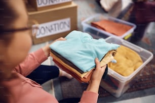 Gros plan d’une femme triant sa garde-robe dans des boîtes pour l’association caritative.