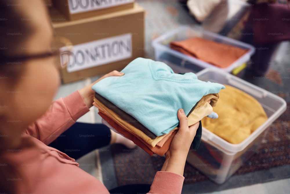 Close-up da mulher classificando o guarda-roupa em caixas para a caridade.