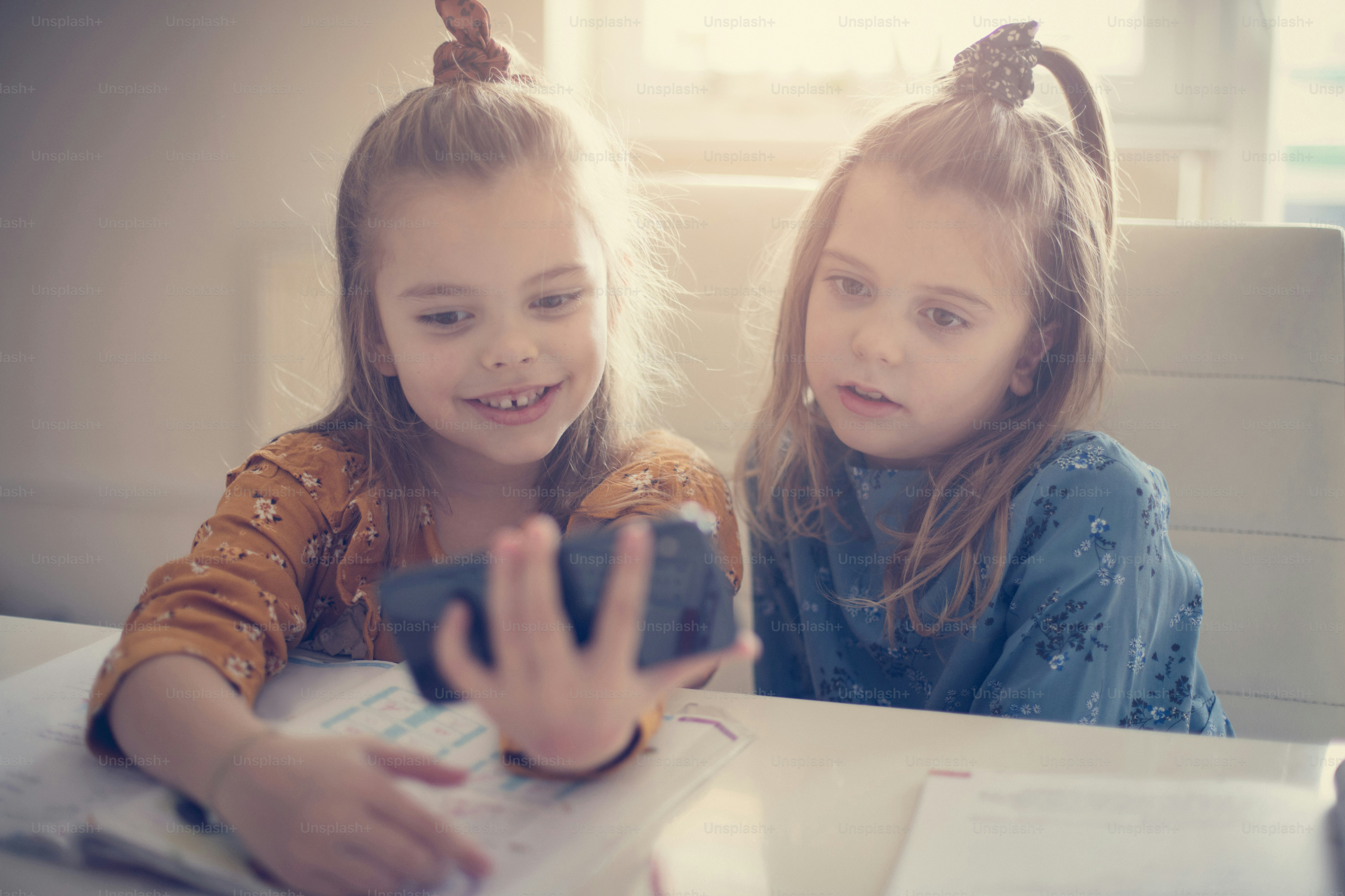 Take a break, and have fun. Two little school girls taking a self portrait. Focus on hand. Close up.