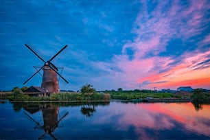 Niederländische ländliche Landschaft mit Windmühlen am berühmten Touristenort Kinderdijk in Holland in der Abenddämmerung mit dramatischem Himmel