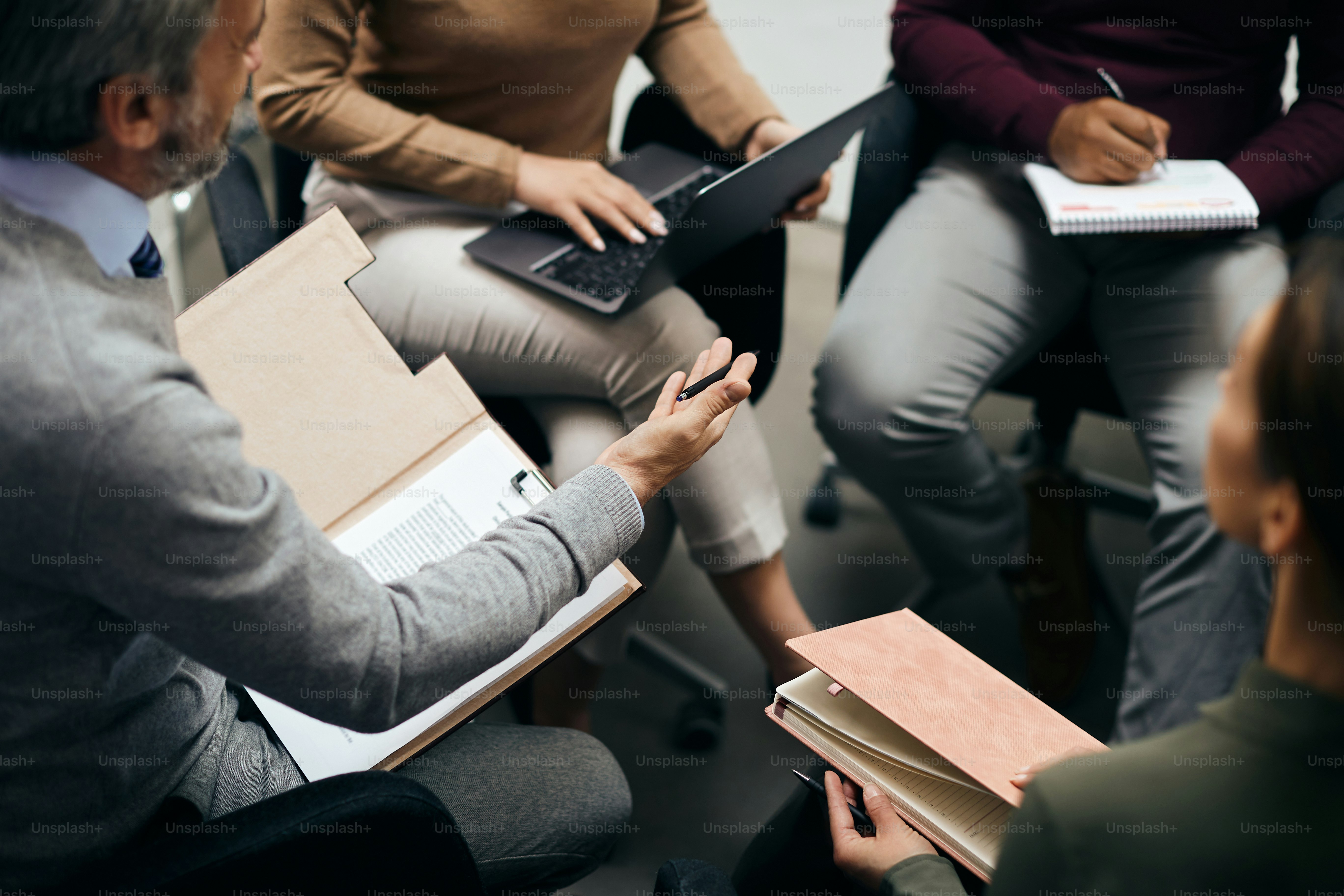 Primo piano del direttore esecutivo che parla con i suoi colleghi durante la riunione di lavoro in ufficio.