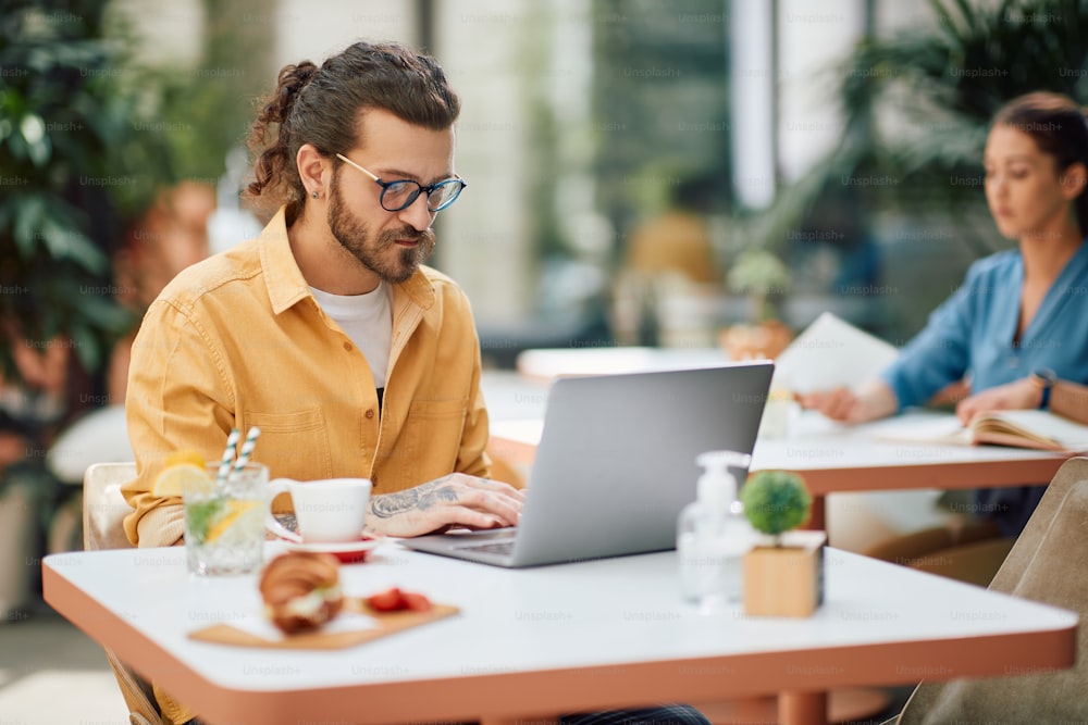 Entrepreneur utilisant un ordinateur tout en travaillant sur sa pause-café dans un café.