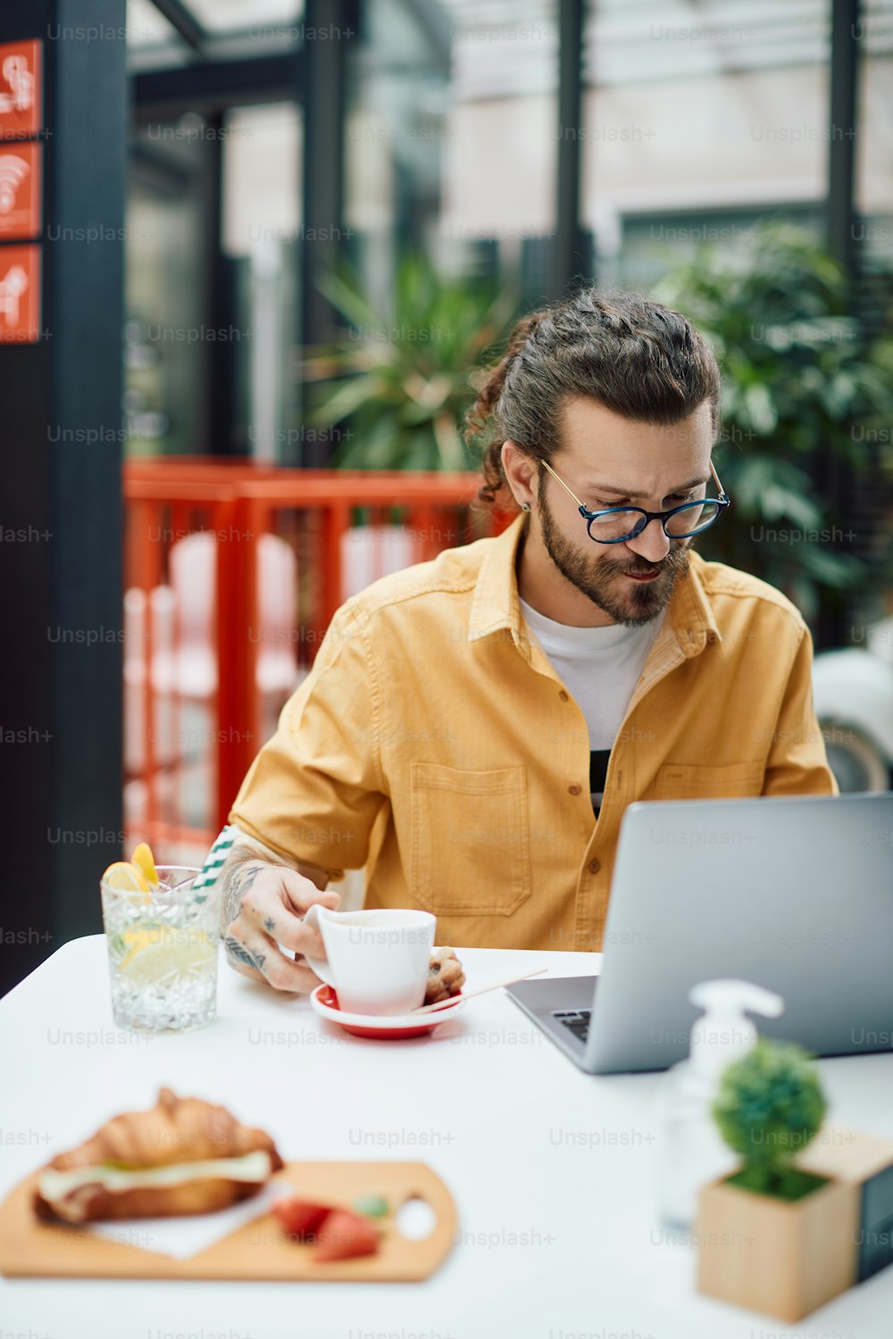 Männliche Unternehmer benutzen Laptop, während sie in einem Café Kaffee trinken.