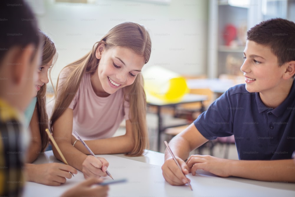 Group work in class. Teenagers students sitting in the classroom and talking. Focus is on background.