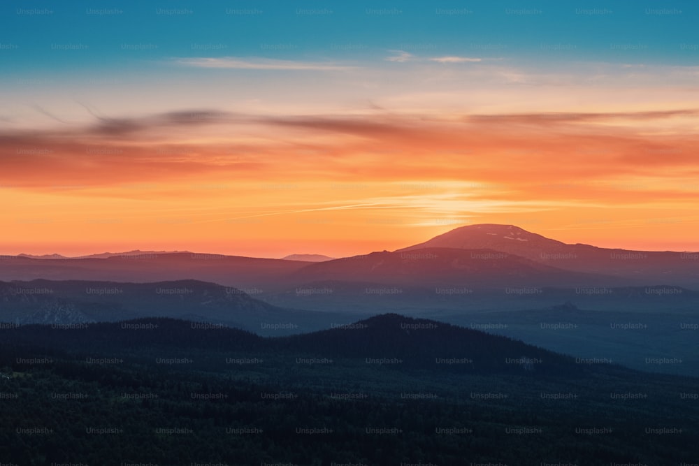 A rocky mountain range covered in the wild woods illuminated by the golden light of the setting sun. A natural Park reserve or hunting grounds. Recreational outdoor tourism